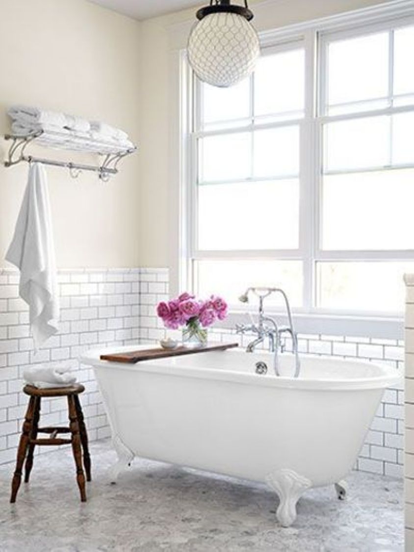 carrara-marble-floor-pairs-with-subway-tile-bathroom-walls-in-white-bathroom-with-clawfoot-tub-with-faucet